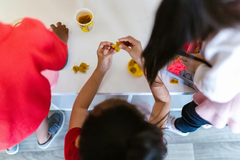 a group of people sitting around a table eating food, play-doh, mustard, photographed from behind, profile image