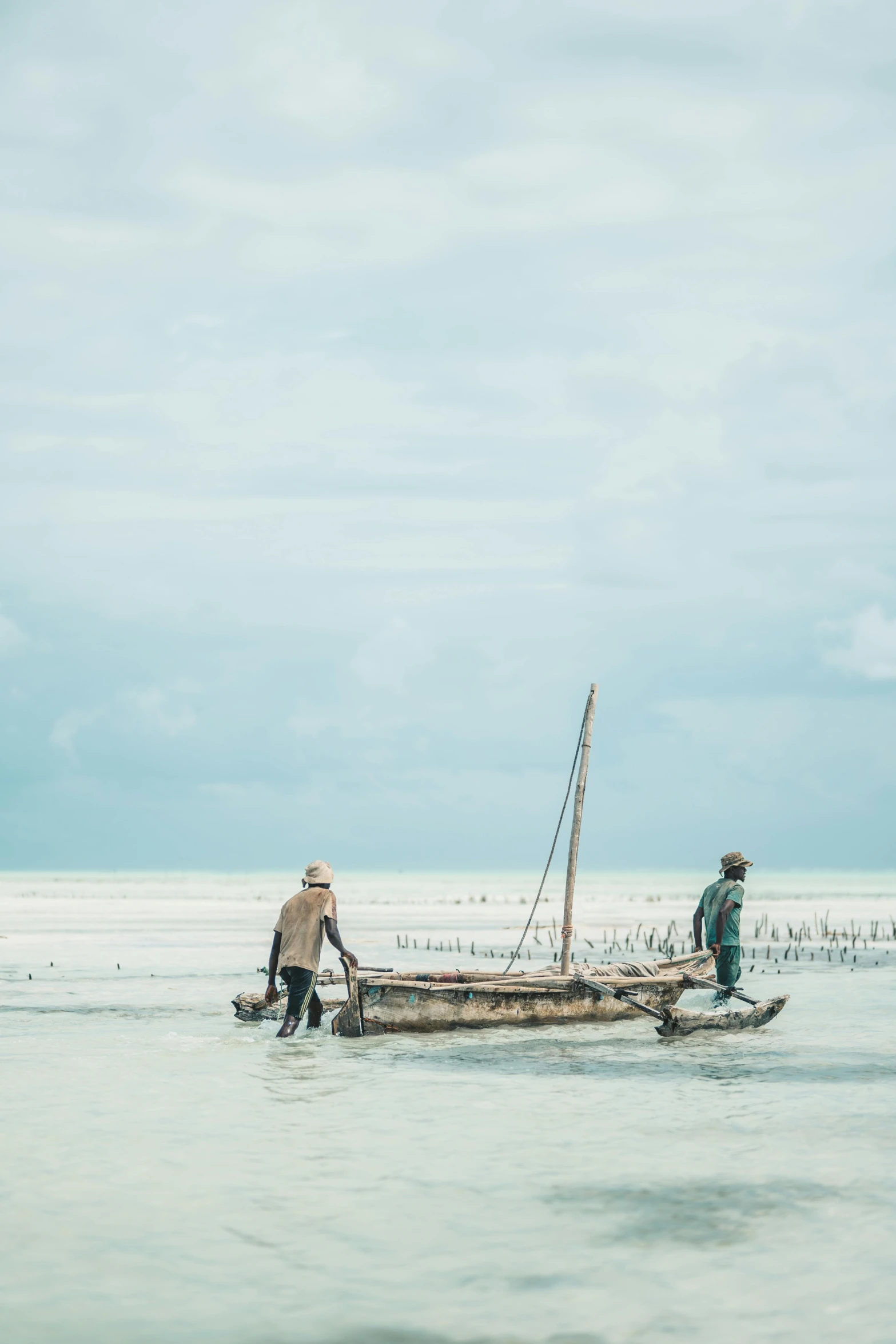 a couple of men standing on top of a boat, unsplash contest winner, mingei, somalia, people at work, lagoon, medium format. soft light