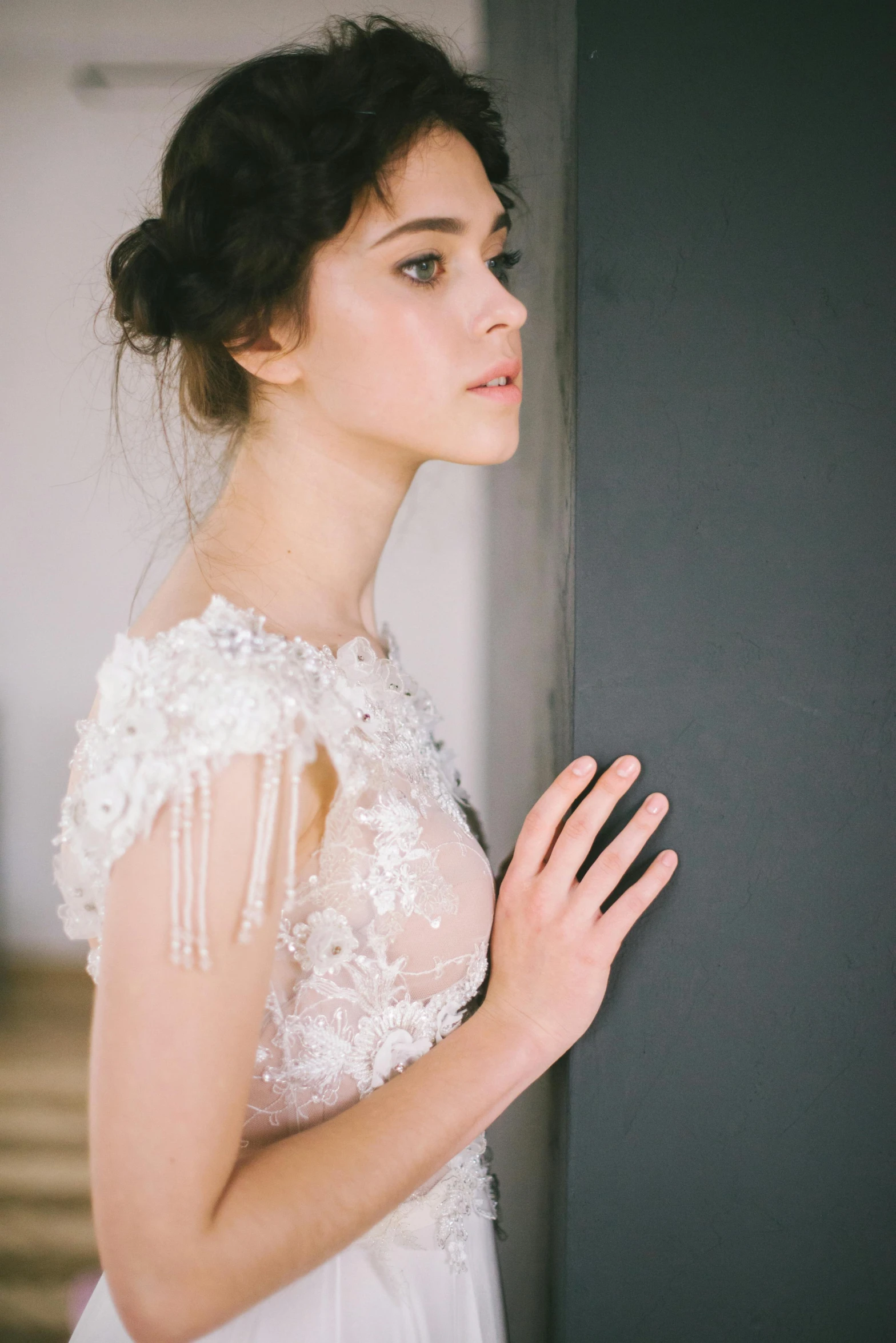 a woman in a wedding dress standing by a wall, inspired by Antoni Brodowski, unsplash, delicate embellishments, looking across the shoulder, promo image, bust view