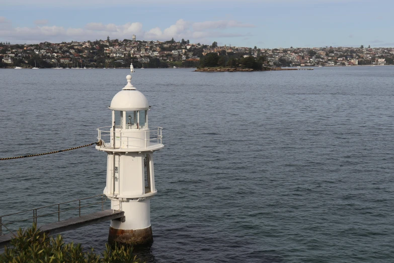 a white light house sitting on top of a body of water, by Epsylon Point, harbour in background, brown, manly, grey