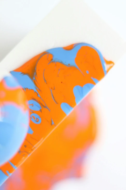 a close up of a skateboard on a white surface, a silk screen, inspired by Michelangelo, action painting, orange and blue, pouring, color gel, neon orange