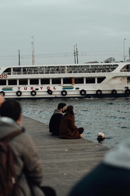 a group of people sitting on a dock next to a boat, pexels contest winner, hurufiyya, turkish and russian, 🚿🗝📝, in love, people watching around