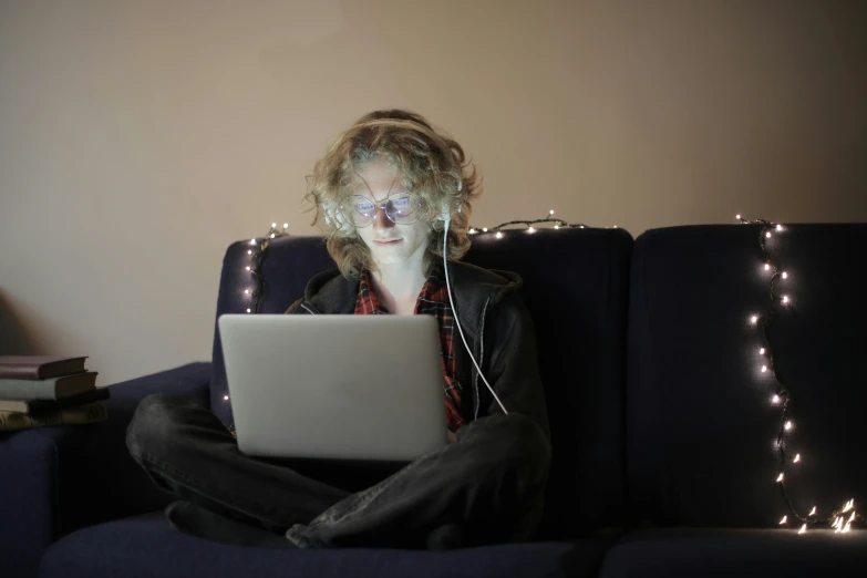 a person sitting on a couch with a laptop, a portrait, inspired by Nan Goldin, computer art, digital glasses, a blond, lit up, boke