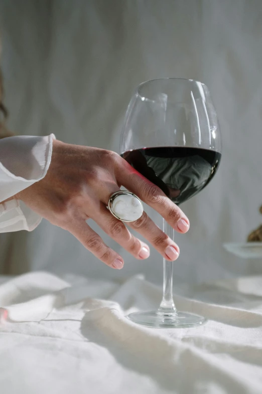 a close up of a person holding a glass of wine, rings, carved white marble, pose 4 of 1 6, linen