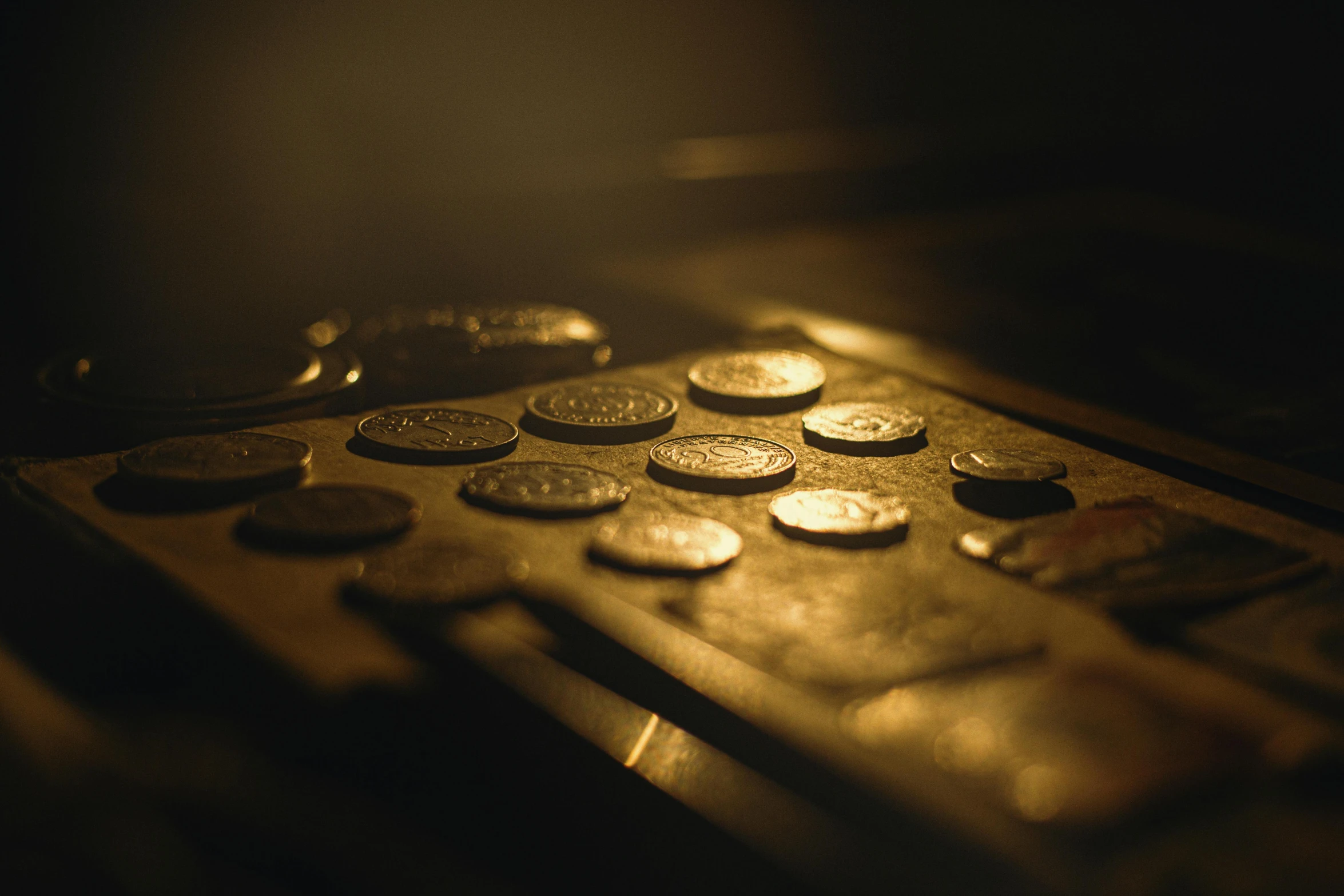 a remote control sitting on top of a wooden table, by Elsa Bleda, art nouveau, gold coins, macro up view metallic, metal plate photograph, backlit