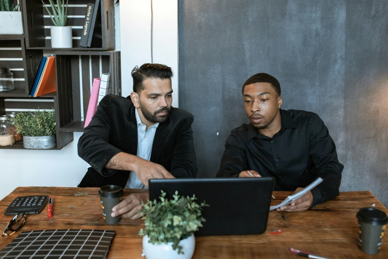 two men sitting at a table looking at a laptop, pexels contest winner, panel of black, people at work, background image, teaching