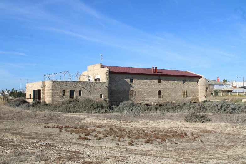 a building sitting on top of a dirt field, les nabis, near the sea, mills, the back rooms