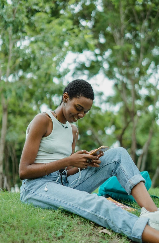 a woman sitting on the grass using a cell phone, by Lily Delissa Joseph, happening, brown skinned, playing games, high resolution image, multiple stories