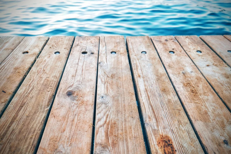 a wooden dock with water in the background, by Niko Henrichon, unsplash, clear detailed view, archimedes, the deck of many things, next to a pool