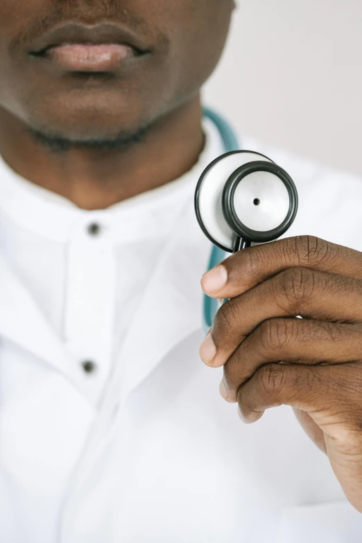 a close up of a person holding a stethoscope, man is with black skin, wearing a white hospital gown, 🚿🗝📝, scholarly