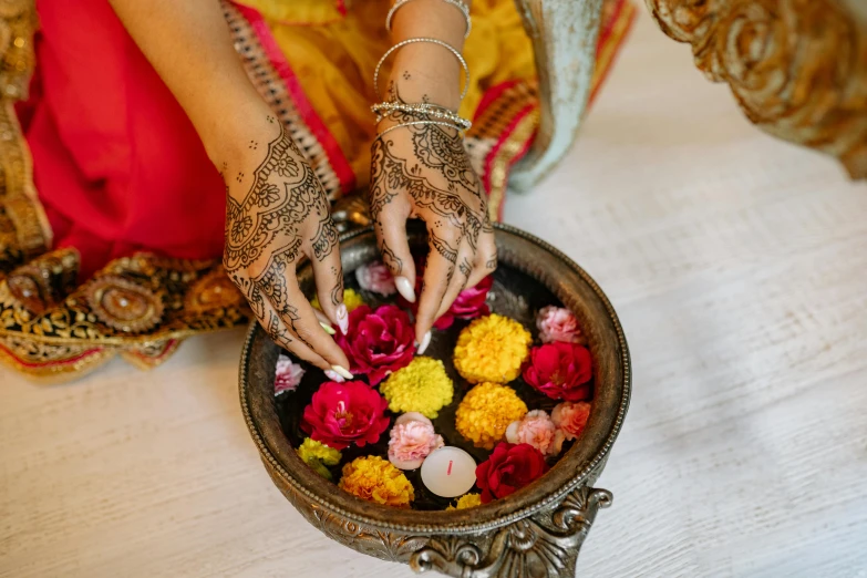 a close up of a person holding a bowl of flowers, mehndi patterns, lamps and flowers, blessing hands, thumbnail