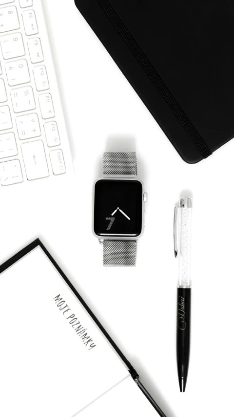 a laptop computer sitting on top of a desk next to a keyboard, a black and white photo, by Robbie Trevino, pexels contest winner, minimalism, silver sports watch, 256x256, chrome outfit, app icon