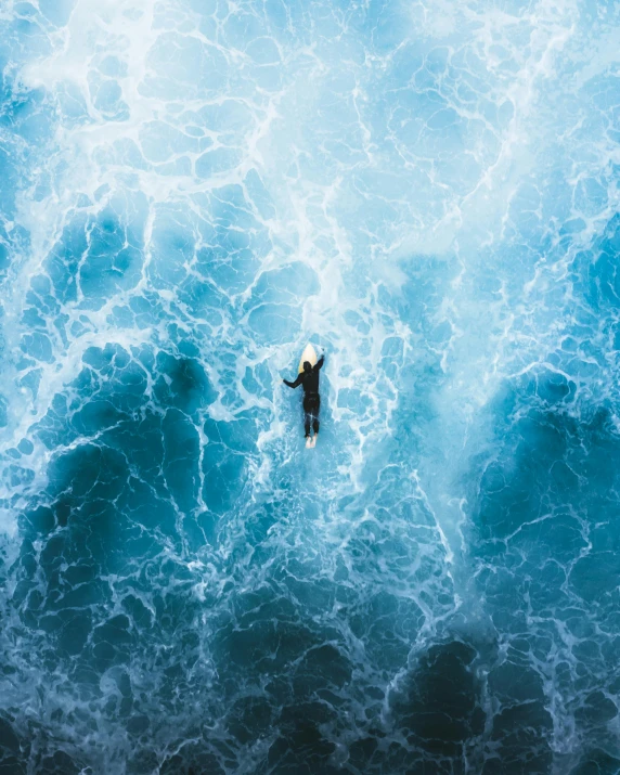 a person on a surfboard in the middle of the ocean, an album cover, unsplash contest winner, helicopter view, wave frequencies, iceland photography, 2019 trending photo