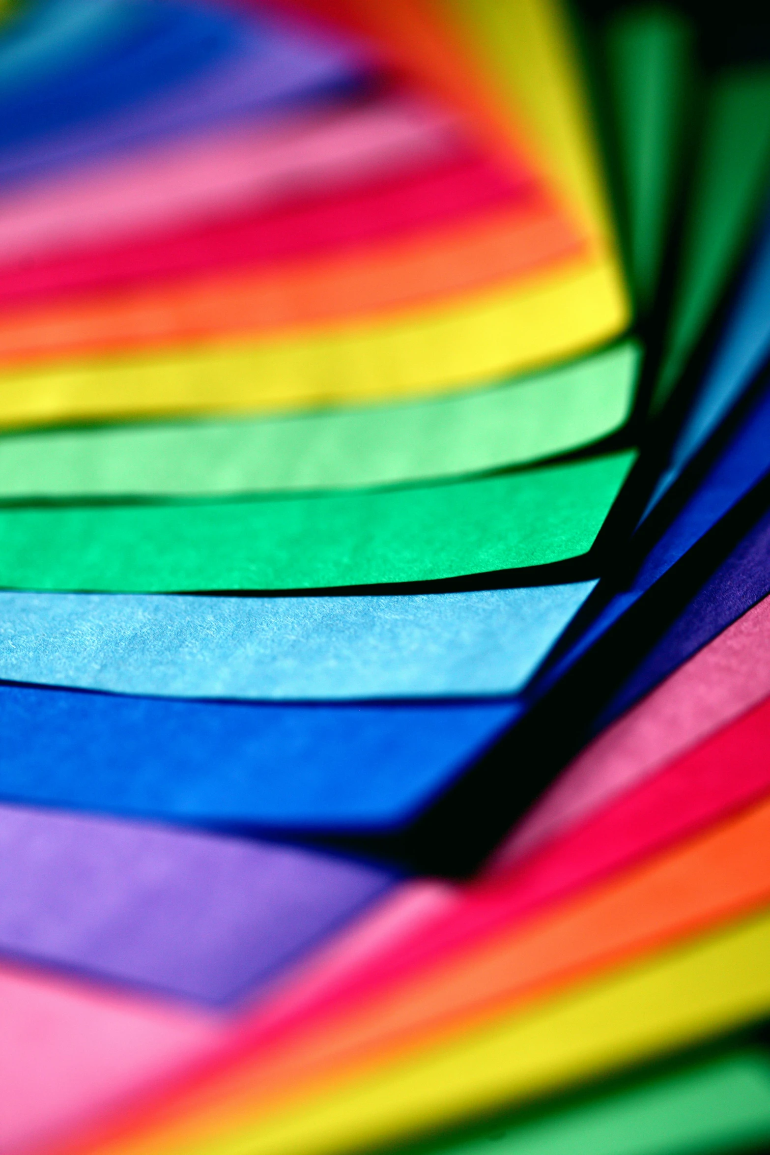 a bunch of colored papers stacked on top of each other, rainbow colours, up-close, 2 5 6 colours