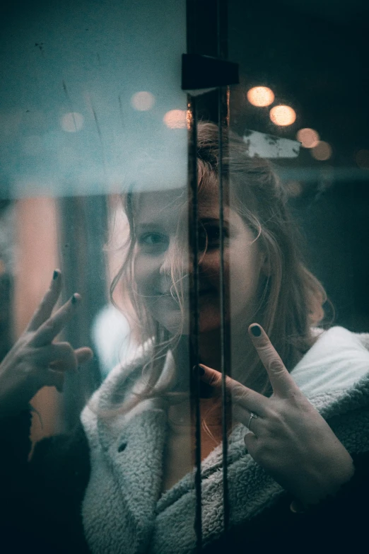 a woman standing in front of a mirror making a peace sign, inspired by Elsa Bleda, pexels contest winner, realism, raining outside the window, creepy smile, in an elevator, desaturated