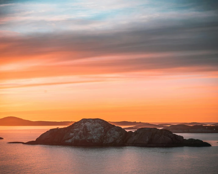 a small island in the middle of a body of water, by Jesper Knudsen, pexels contest winner, romanticism, warm sunset colors, archipelago, hills and ocean, grey