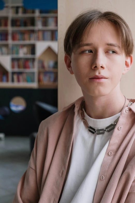 a young man standing in front of a bookshelf, an album cover, inspired by Aleksander Gine, trending on pexels, hyperrealism, wearing collar on neck, androgynous person, vitalik buterin, youtube video screenshot