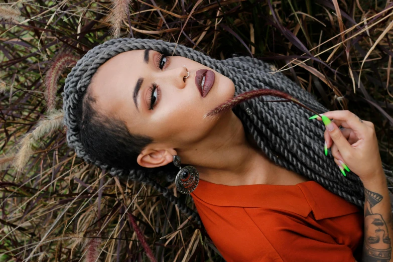 a woman laying on top of a pile of grass, a portrait, trending on pexels, afrofuturism, sexy lips :5 stylish, twisted braids, portrait image, thumbnail