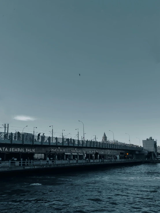 a black and white photo of a bridge over a body of water, a matte painting, pexels contest winner, hurufiyya, cold blue colors, in the middle of the city, turkish and russian, low quality photo
