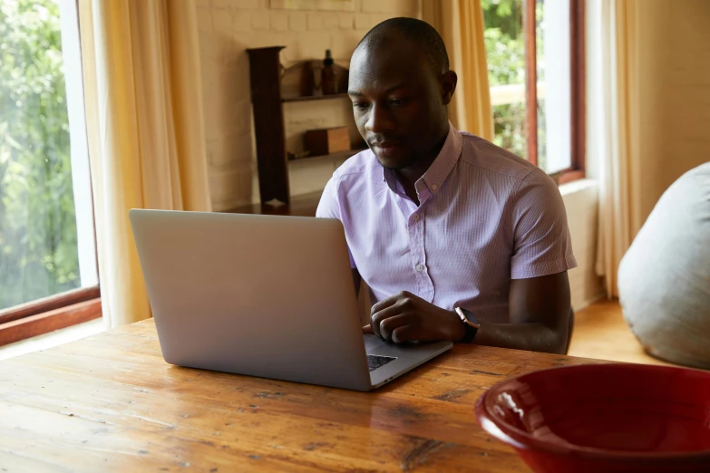 a man sitting at a table using a laptop computer, by Carey Morris, emmanuel shiru, rustic, brown