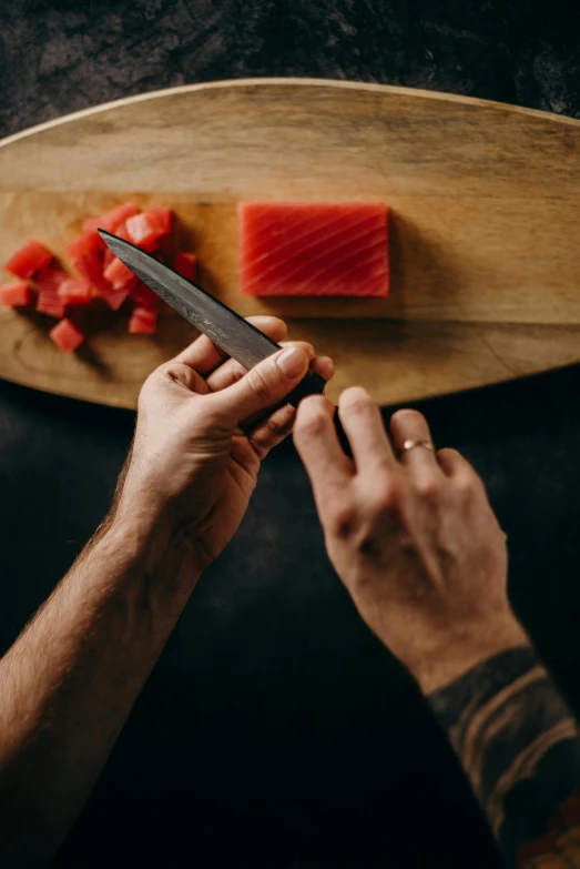 a person cutting up a piece of fish on a cutting board, holding a katana, 2019 trending photo, sitting on man's fingertip, medium angle