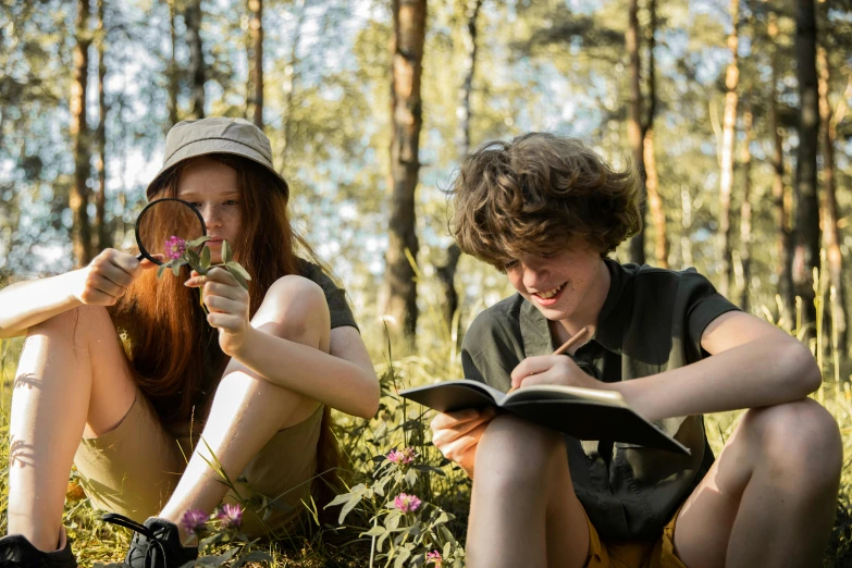 a couple of people that are sitting in the grass, pexels contest winner, plein air, brunette boy and redhead boy, nature journal, magnifying glass, teenage girl