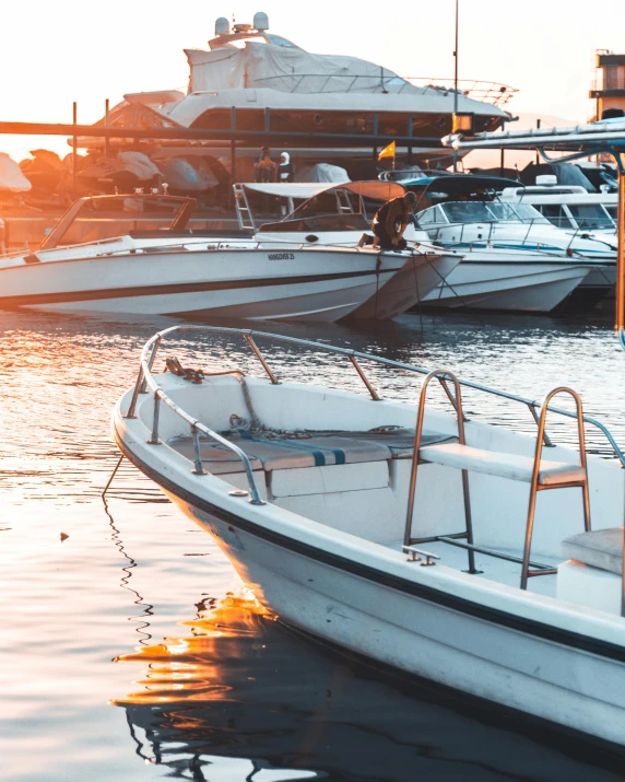 a number of boats in a body of water, in the sunset, boat dock, sitting down, in the sun