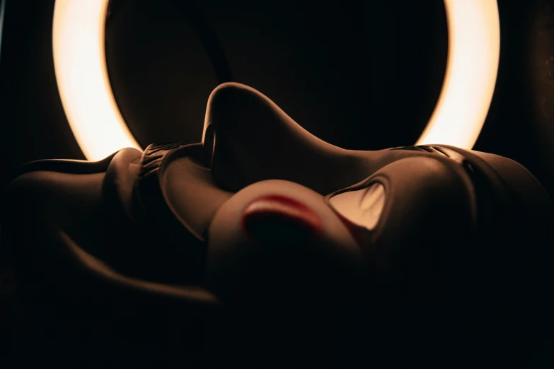 a close up of a person laying in front of a light, smooth oval head, submissive