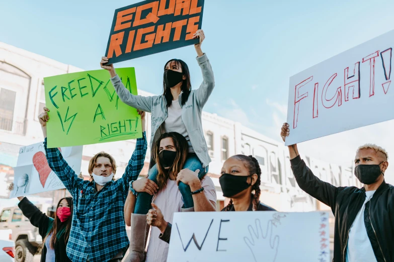a group of people holding signs in the air, by Julia Pishtar, trending on pexels, lesbians, background image, fights, ethnic group