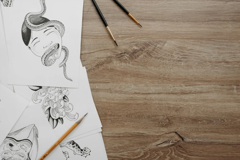 a bunch of drawings sitting on top of a wooden table, inspired by Eishōsai Chōki, trending on pexels, background image, tattoo design sketch, graphic templates, wood effect