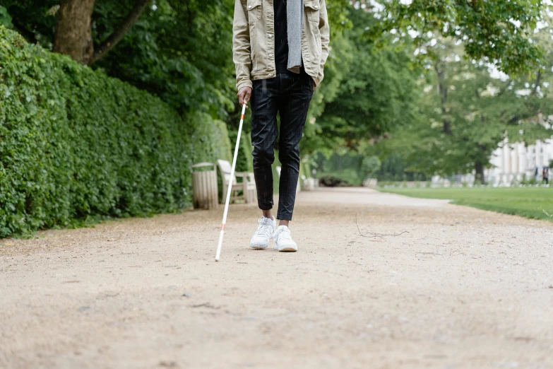 a man walking down a path with a cane, unsplash, realism, wearing only pants, artificial limbs, dezeen, at a park