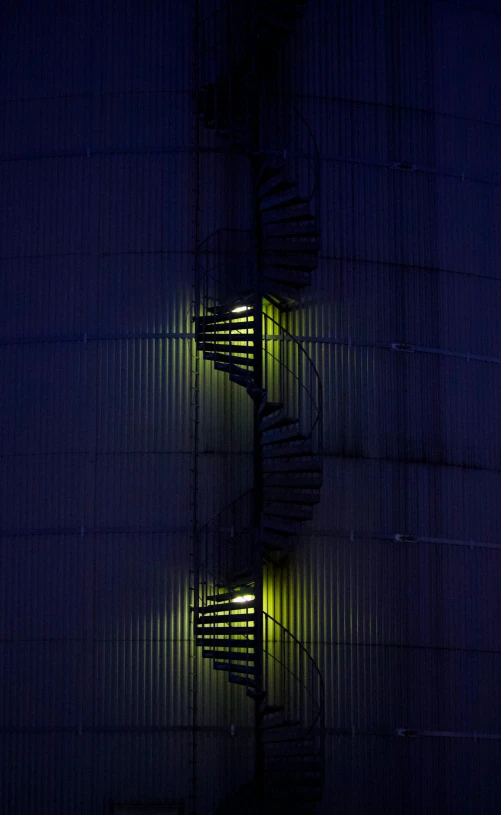 a spiral staircase lit up at night in front of a building, industrial colours, photographed for reuters, silo, david noton