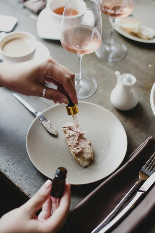 a person sitting at a table with a plate of food, charcoal and champagne, pink, holding knife, unrefined sparkling gold nugget