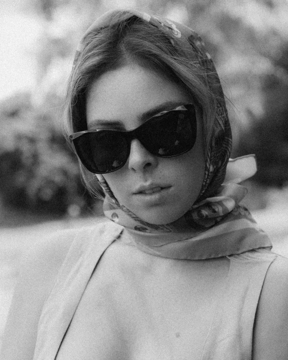 a black and white photo of a woman wearing sunglasses, inspired by Anita Malfatti, arabesque, wearing a scarf, aubrey plaza, vintage color, square