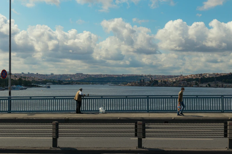 a couple of people walking across a bridge, by Yasar Vurdem, istanbul, expansive view, midday photograph, fishing