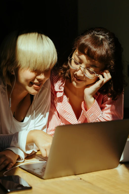 a couple of women sitting at a table with a laptop, trending on pexels, renaissance, one blonde and one brunette, nerds, bottom angle, low key light