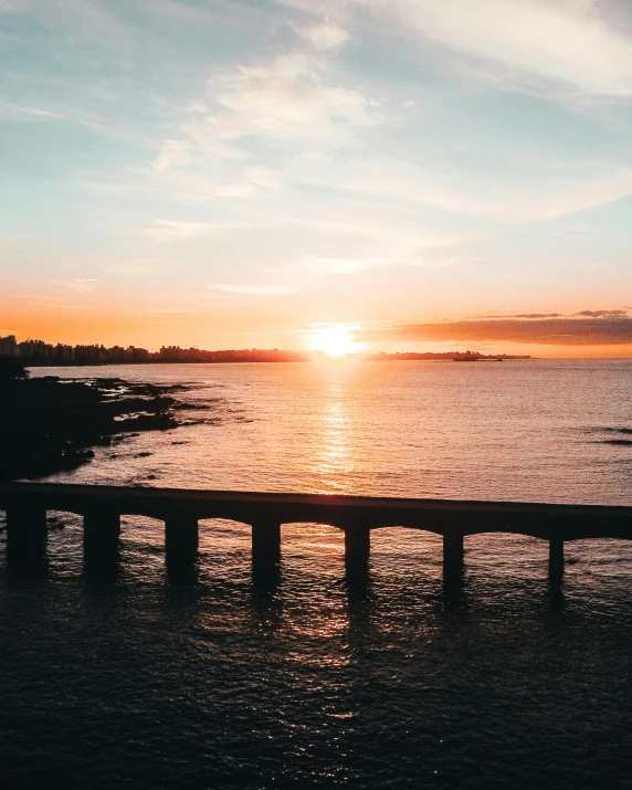 the sun is setting over a body of water, a polaroid photo, pexels contest winner, on a bridge, view of sea, but not pretty, drone footage