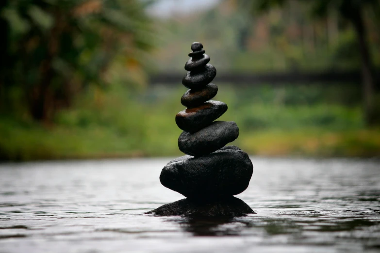 a stack of rocks sitting on top of a body of water, an album cover, unsplash, environmental art, black, balancing the equation, rain lit, sculpture