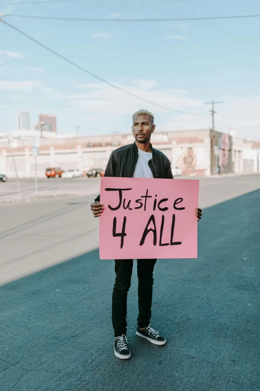 a man holding a sign that says justice 4 all, an album cover, trending on pexels, queer, unfinished, male hero, billboard image