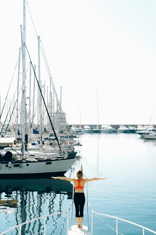 a woman standing on a boat in the water, marbella, yoga, docked at harbor, three masts