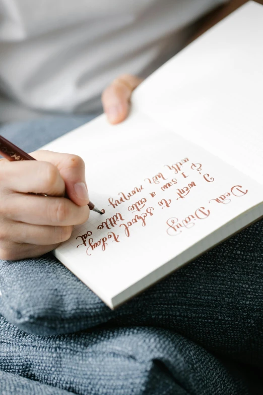 a person holding a pen and writing on a piece of paper, inspired by Ruth Jên, unsplash, letterism, on canvas, calligraphic poetry, thumbnail, multiple stories