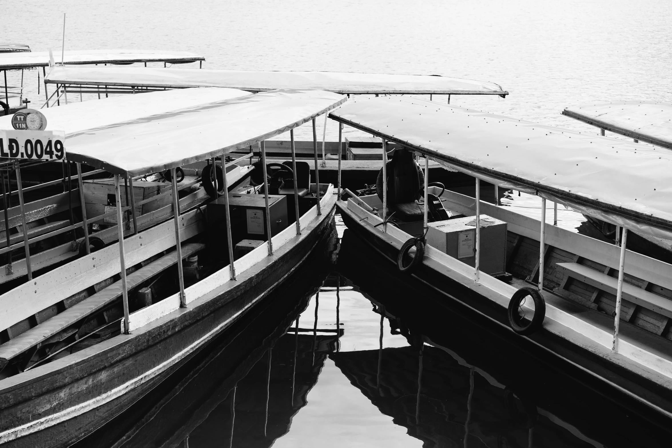 a couple of boats that are sitting in the water, a black and white photo, by Yosa Buson, hurufiyya, low detailed, moored, as photograph