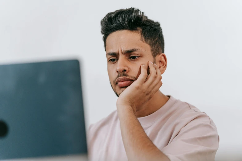 a man sitting in front of a laptop computer, trending on pexels, noticeable tear on the cheek, te pae, manly, brown stubble