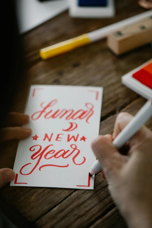 a person writing happy new year on a piece of paper, by Julia Pishtar, trending on pexels, behance lemanoosh, card template, suntur, promotional image