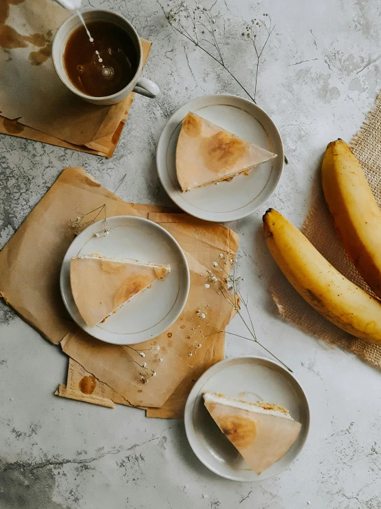 a table topped with plates of food next to bananas, a still life, by Emma Andijewska, trending on unsplash, rice paper texture, coffee stain, thumbnail, low quality photo