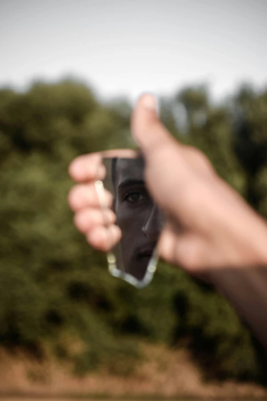 a close up of a person holding a glass of wine, a picture, inspired by Anna Füssli, broken mirror, photograph captured in a forest, shaped focus, reflective faces