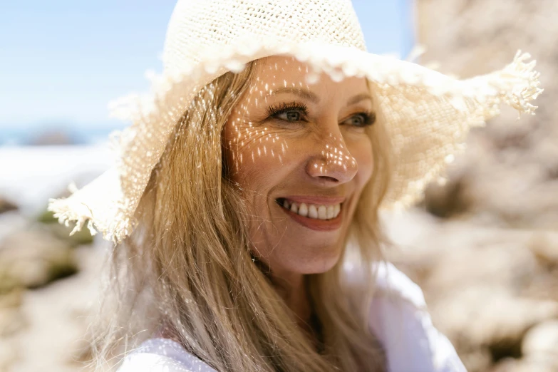 a close up of a person wearing a hat, on the beach, she is smiling, white, portrait image