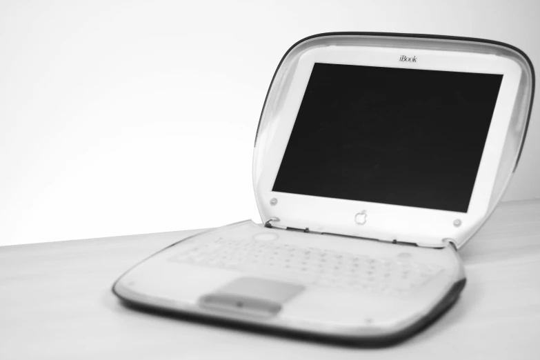 a white laptop computer sitting on top of a wooden table, by Adam Rex, historical image, jewel case, jony ive, black and white image