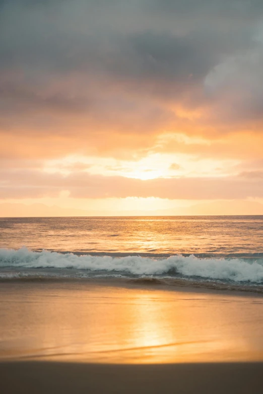 a man riding a surfboard on top of a sandy beach, unsplash, romanticism, the glimmering orange dawn, shades of gold display naturally, kauai, photo of the middle of the ocean