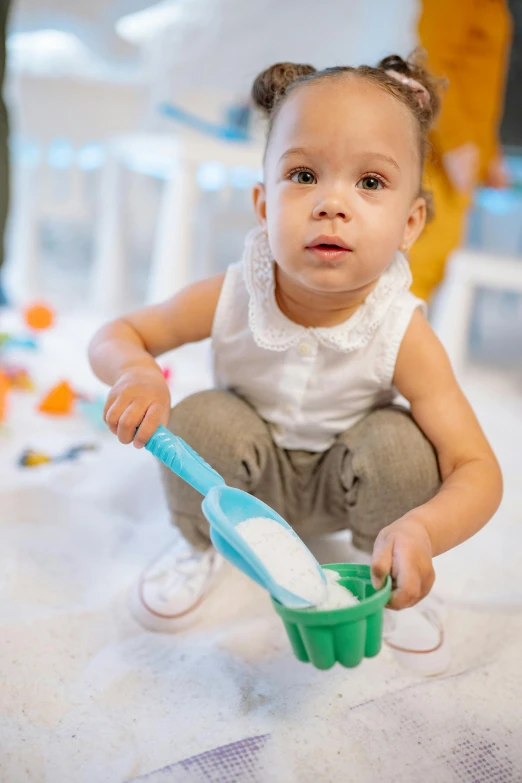 a little girl sitting on the floor with a toothbrush, pexels, powdered sugar, activity play centre, with one small, white sand